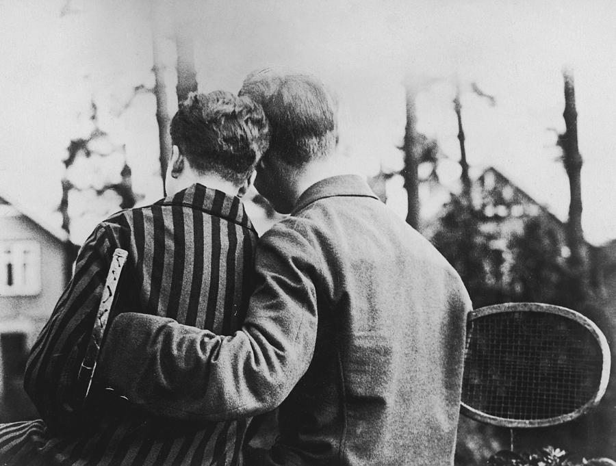 Couple carrying tennis rackets, close-up, rear view (B&W) Photograph by Fpg