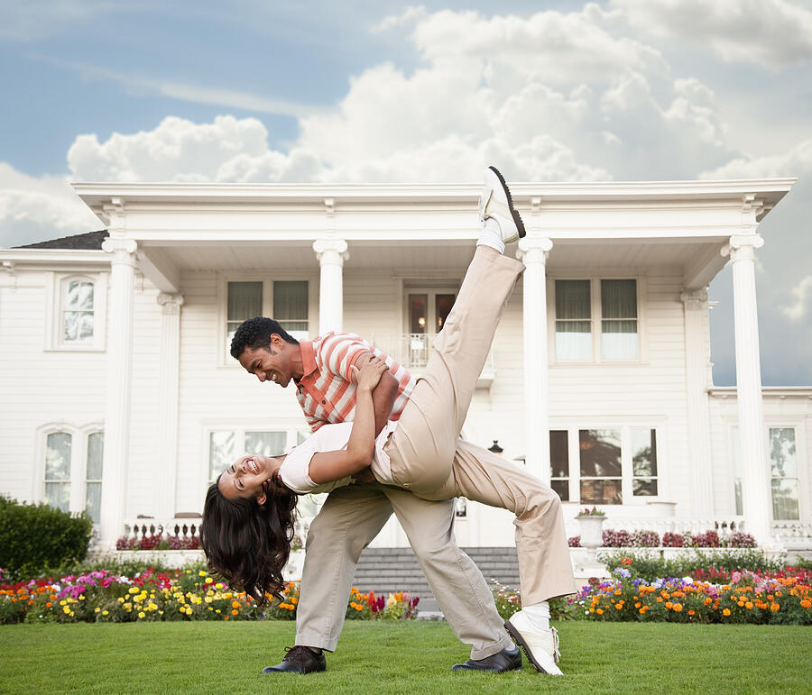 Couple dancing in front of luxury home Photograph by Shalom Ormsby Images Inc