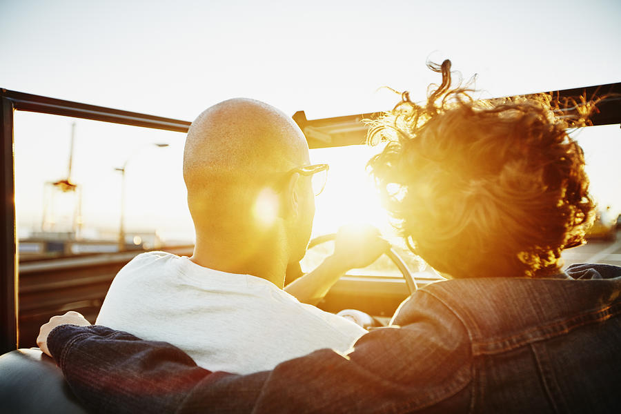 Couple driving convertible at sunset Photograph by Thomas Barwick