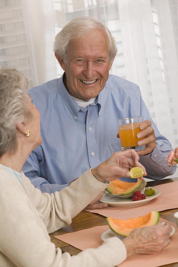 Couple eating cantaloupe and drinking juice Photograph by Comstock Images