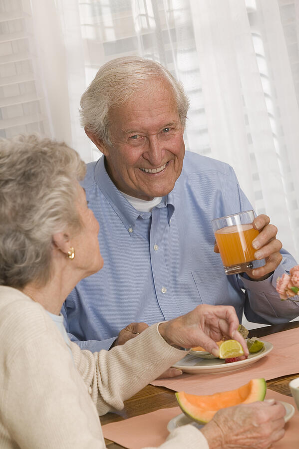Couple eating fruit and drinking juice Photograph by Comstock Images