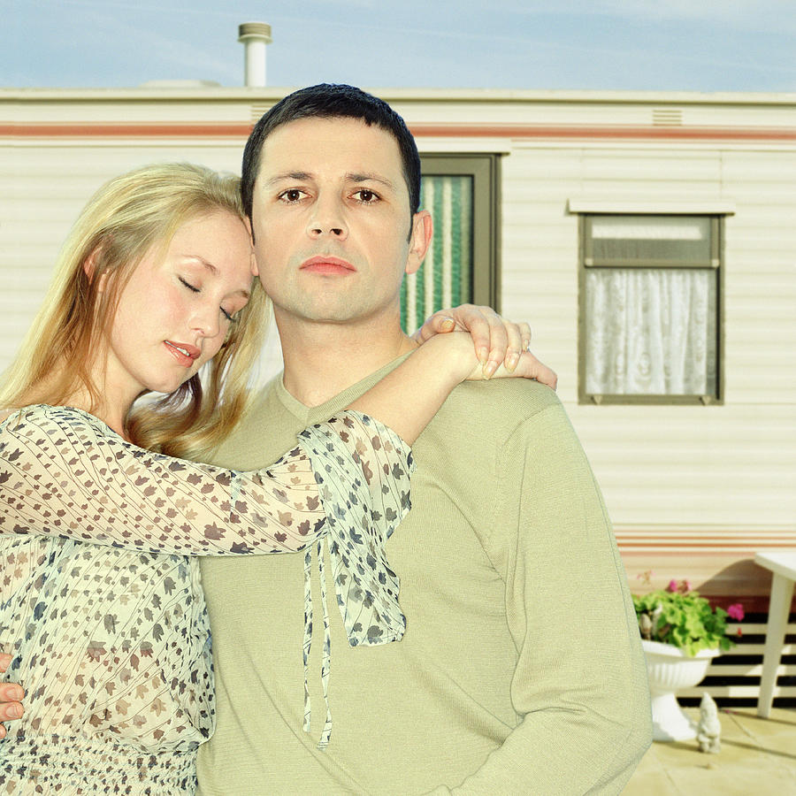 Couple embracing in front of caravan, close-up, portrait Photograph by Microzoa
