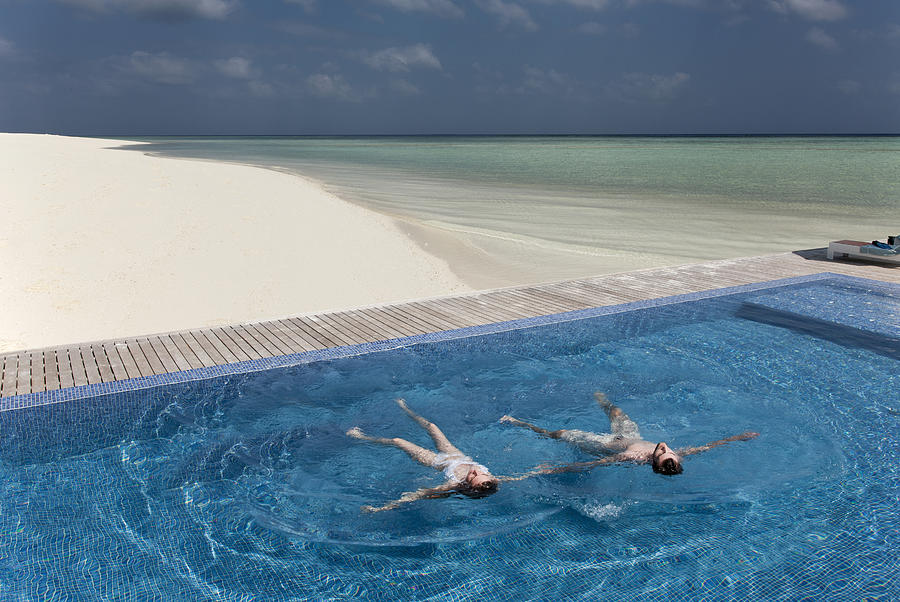 Couple floating in infinity pool on beach Photograph by Buena Vista Images