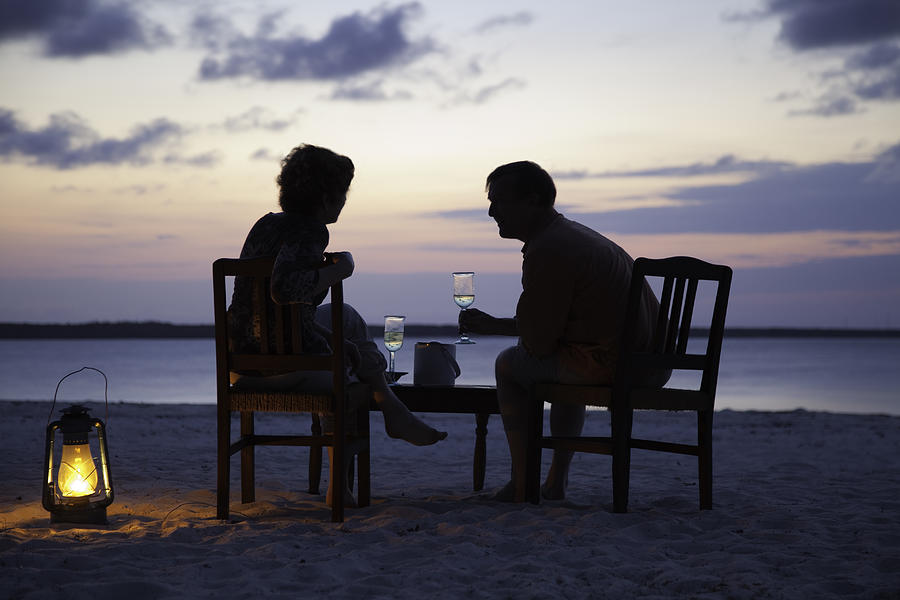 Couple having drinks on beach at sunset, Zanzibar Photograph by Karen Desjardin