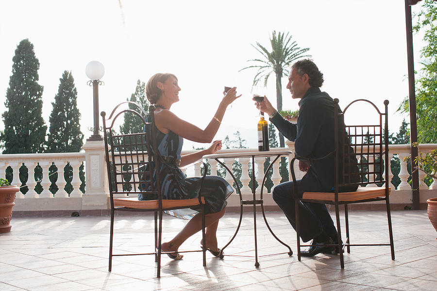 Couple having wine on balcony Photograph by Tom Merton