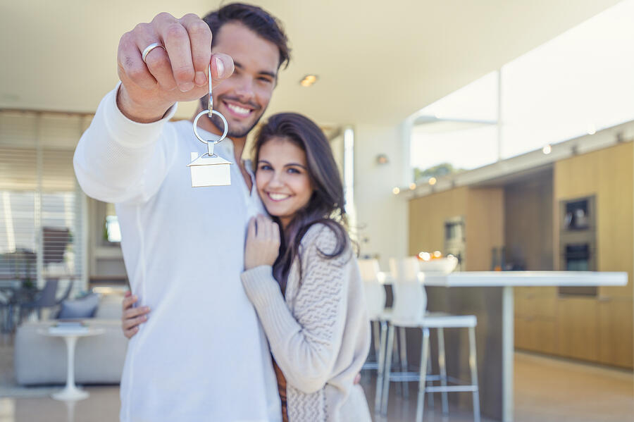 Couple holding a house key in their new home. Photograph by Courtneyk