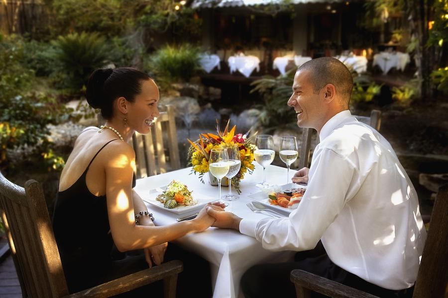 Couple holding hands at restaurant table Photograph by Colin Anderson Productions pty ltd