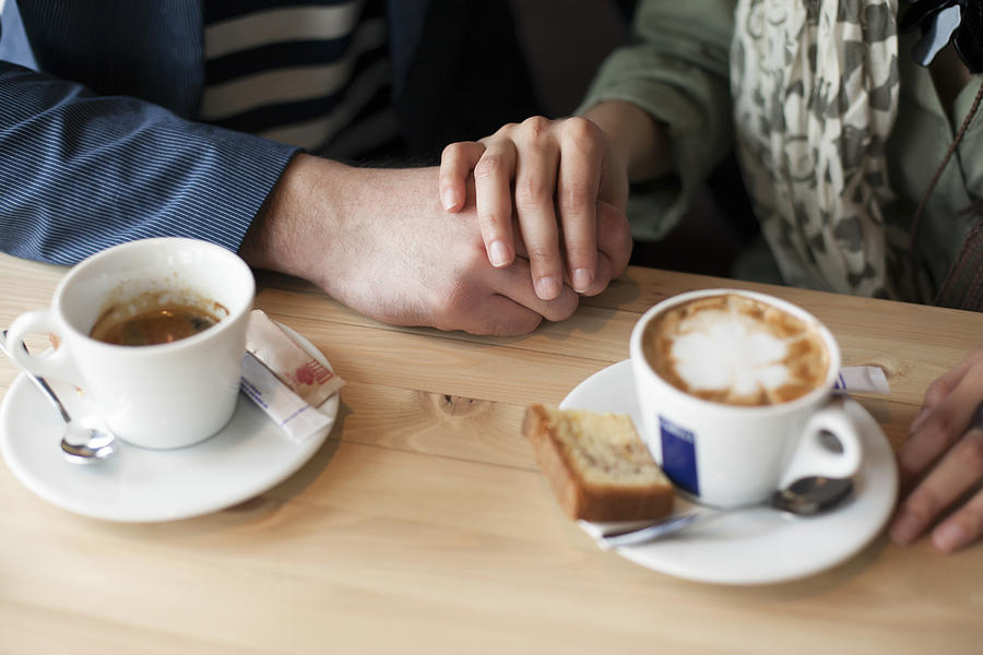 Couple holding hands in cafe Photograph by Lumina Images