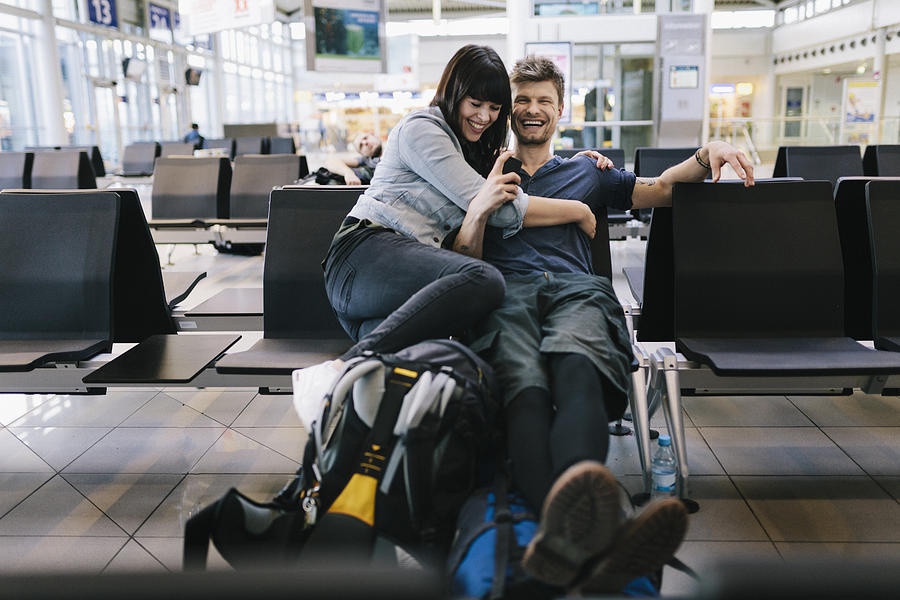 Couple in Airport departure lounge  Photograph by Hinterhaus Productions