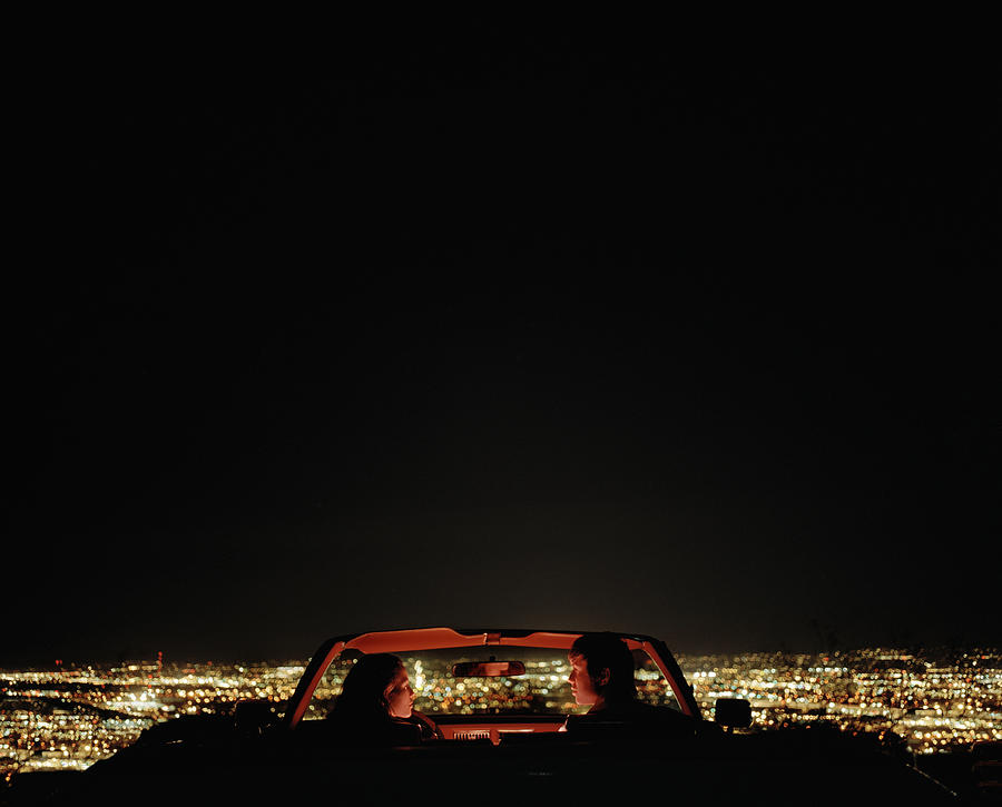 Couple in convertible overlooking city, rear view Photograph by Matthias Clamer