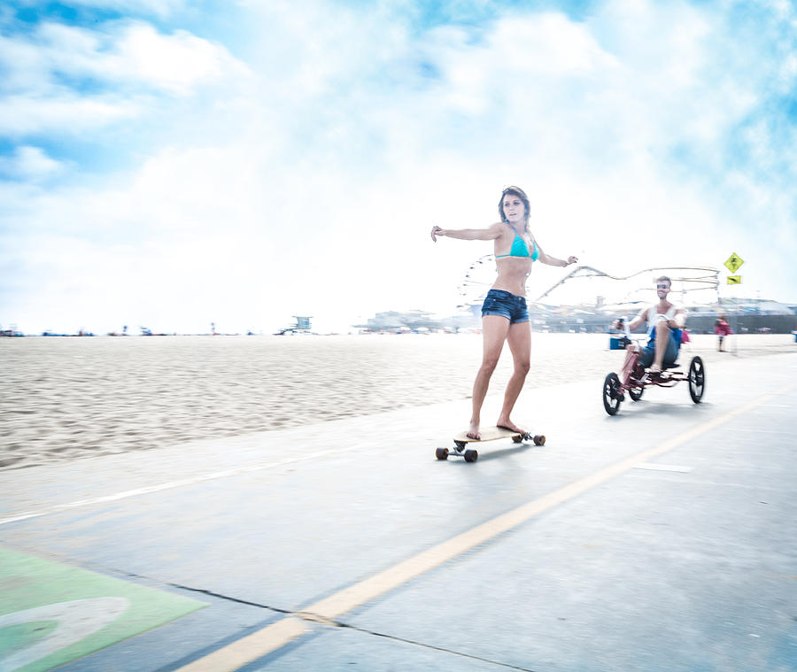 Couple in LA - riding three wheel bicycle and doing skateboarding Photograph by Itsskin