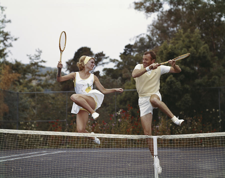 Couple jumping on tennis court, smiling Photograph by Tom Kelley Archive