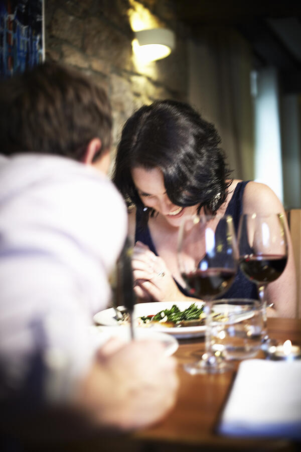 Couple laughing at dinner in restaurant Photograph by Cultura RM Exclusive/Liam Norris