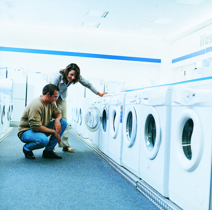 Couple Looking at a Washing Machine in An Aisle of a Department Store Photograph by Digital Vision.