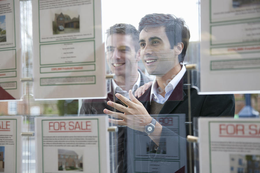 Couple looking into estate agents window Photograph by Chris Whitehead