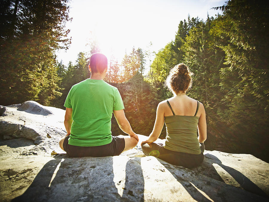 Couple meditating on rock in forest Photograph by Thomas Barwick