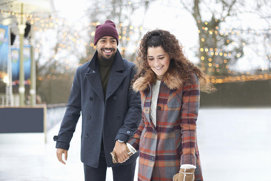 Couple on ice rink holding hands smiling Photograph by Peter Muller