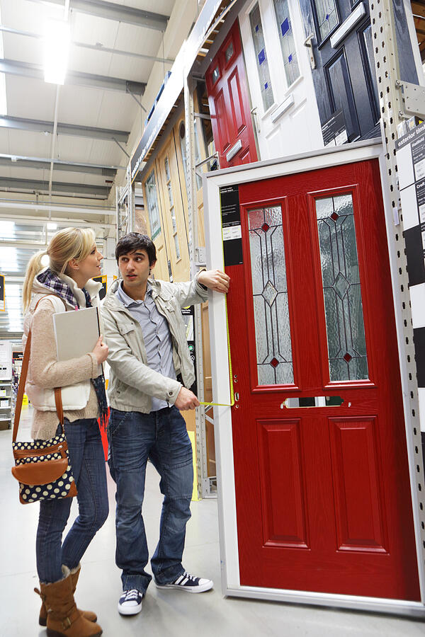 Couple picking new front door in shopping store Photograph by Peter Cade