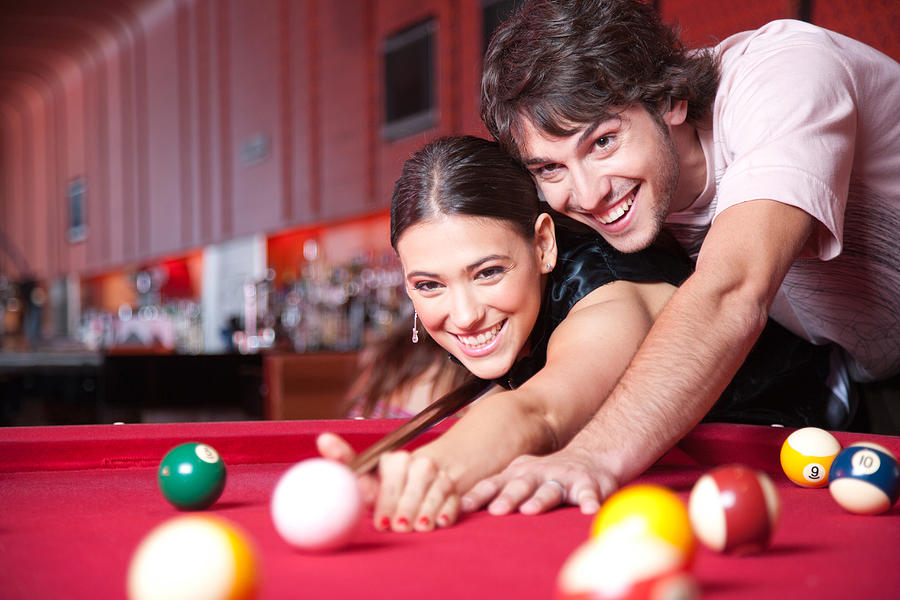 Couple playing pool and smiling Photograph by Paul Bradbury