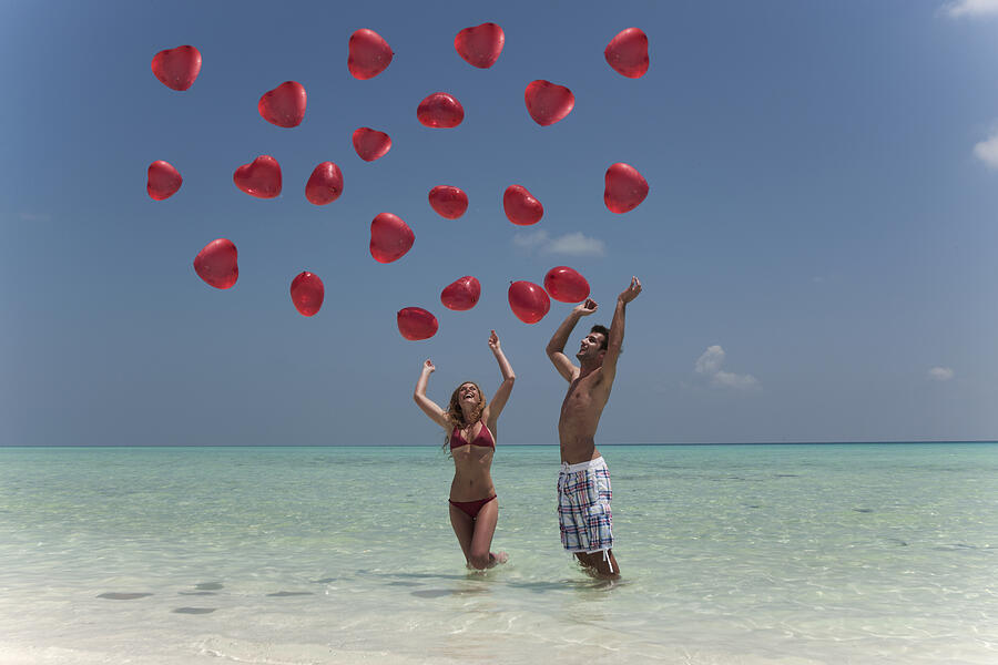 Couple playing with balloons on beach Photograph by Lost Horizon Images