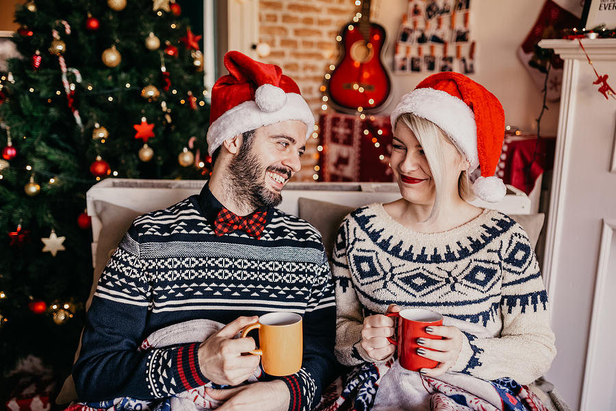Couple relaxing and drinking tea in front of a Christmas tree Photograph by Anchiy