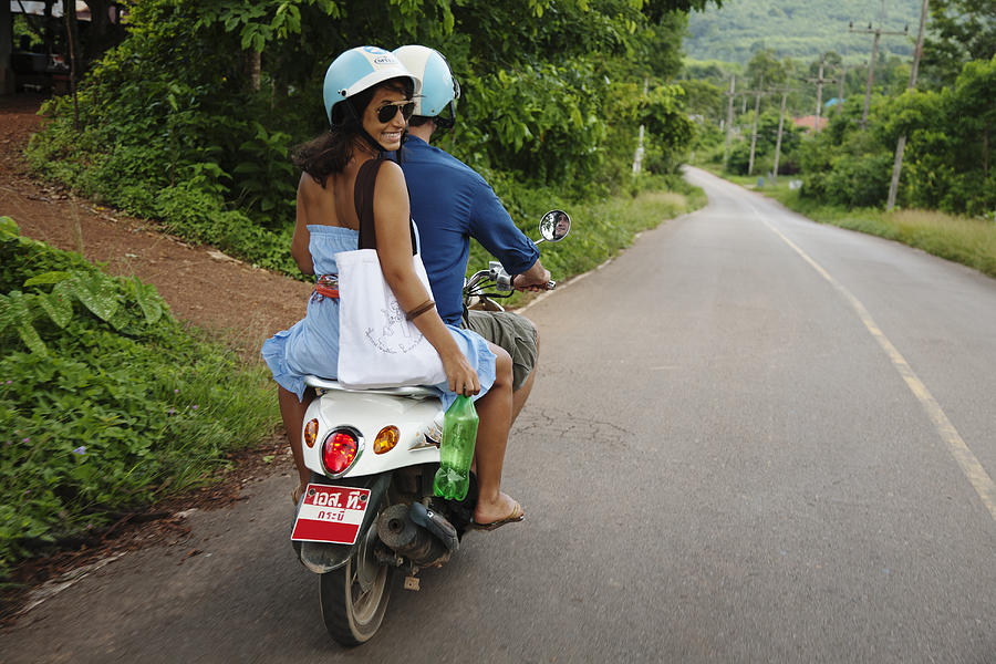Couple riding scooter in remote area Photograph by Blend Images - Roberto Westbrook