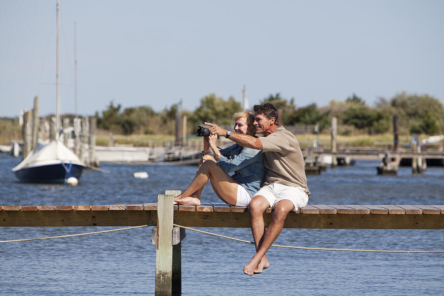 Couple sitting on a dock Photograph by Steve Prezant