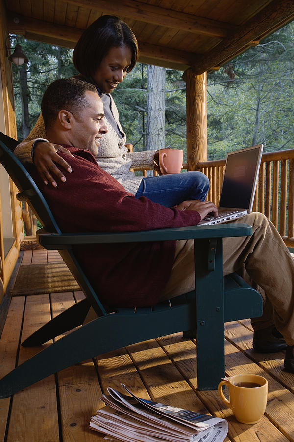 Couple sitting on porch, man working on laptop Photograph by Colorblind