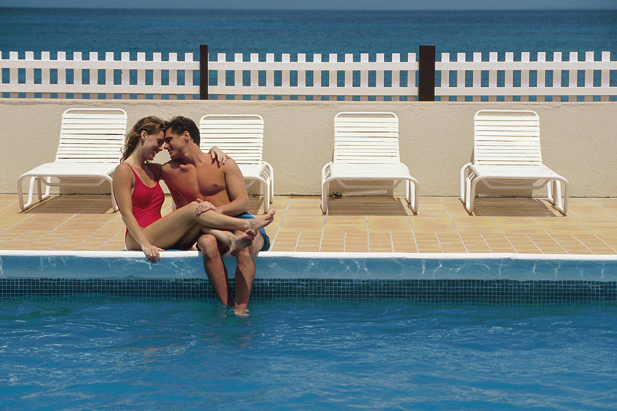 Couple sitting poolside Photograph by Comstock