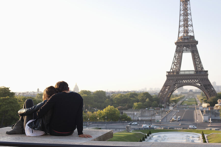 Couple sitting together with the Eiffel Tower in the background, Jardins du Trocadero, Paris, Ile-de-France, France Photograph by ONOKY - Fabrice LEROUGE