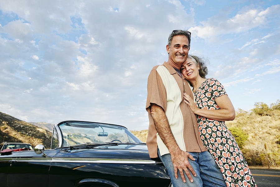 Couple smiling near classic convertible Photograph by Peathegee Inc