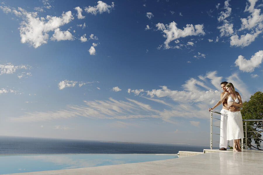 Couple Standing Poolside on a Scenic Coast Photograph by Flying Colours Ltd