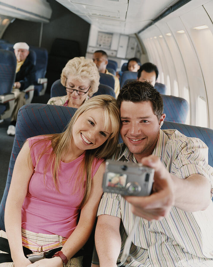 Couple Taking a Picture of Themselves in an Airplane Photograph by Digital Vision.