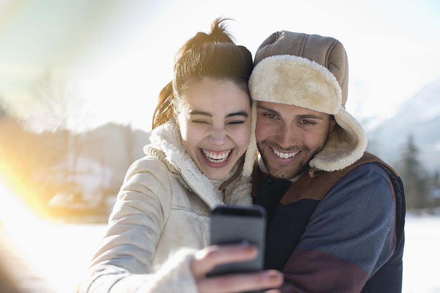 Couple taking selfie in snow Photograph by Caia Image