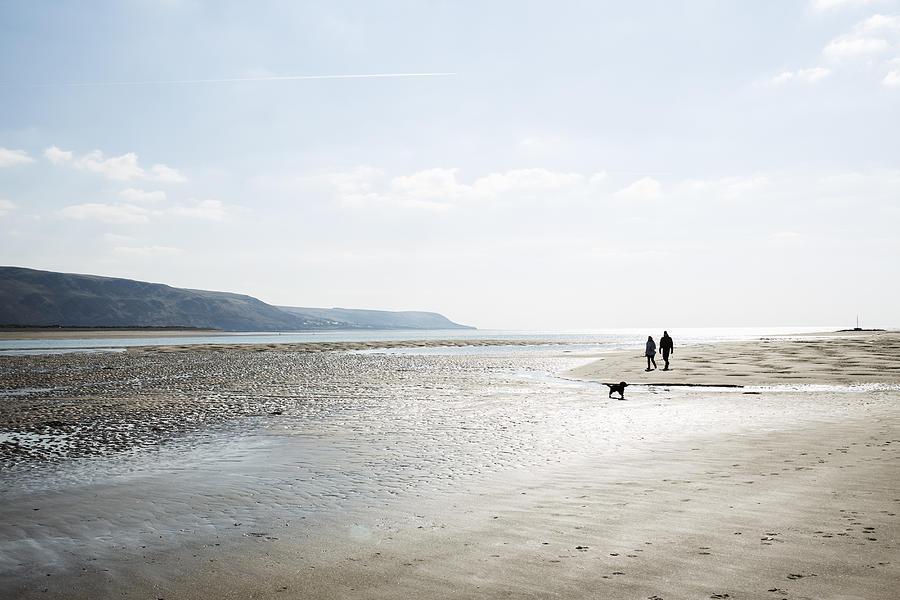Couple walking on beach with dog, North wales. Photograph by Betsie Van der Meer