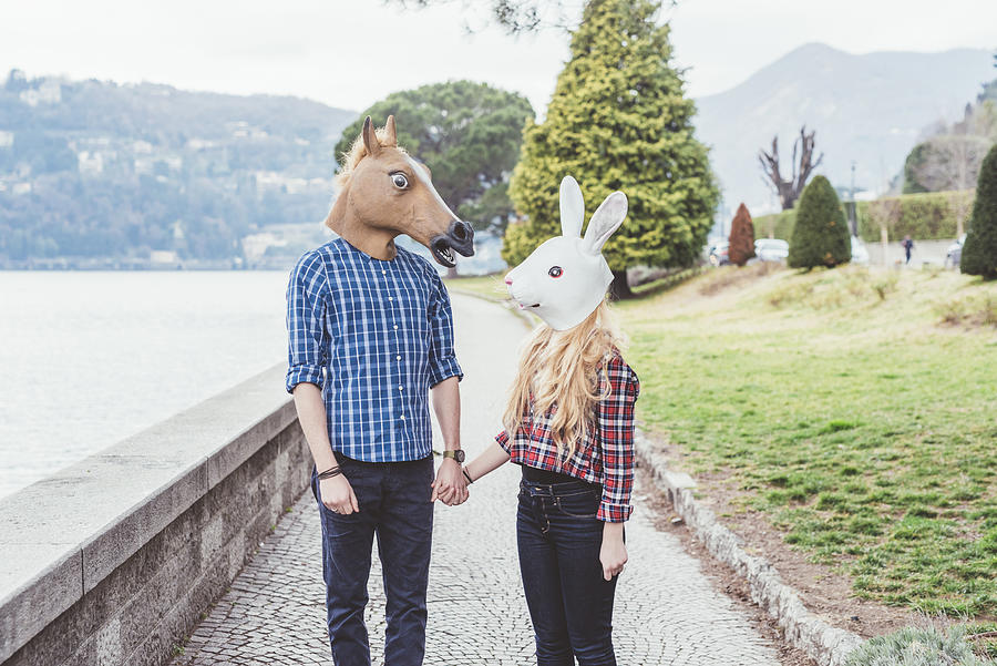 Couple wearing horse and rabbit masks holding hands, Lake Como, Italy Photograph by Eugenio Marongiu
