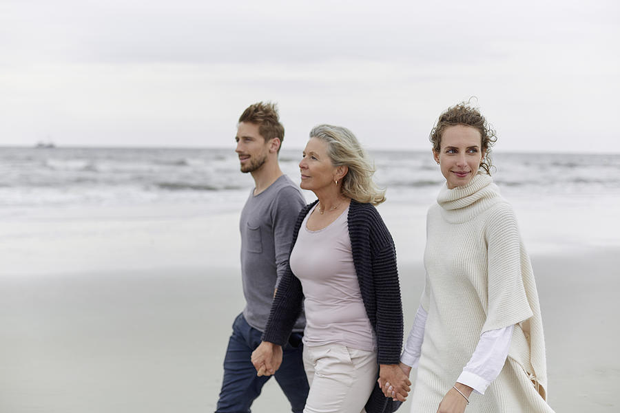 Couple with senior woman walking on the beach Photograph by Oliver Rossi
