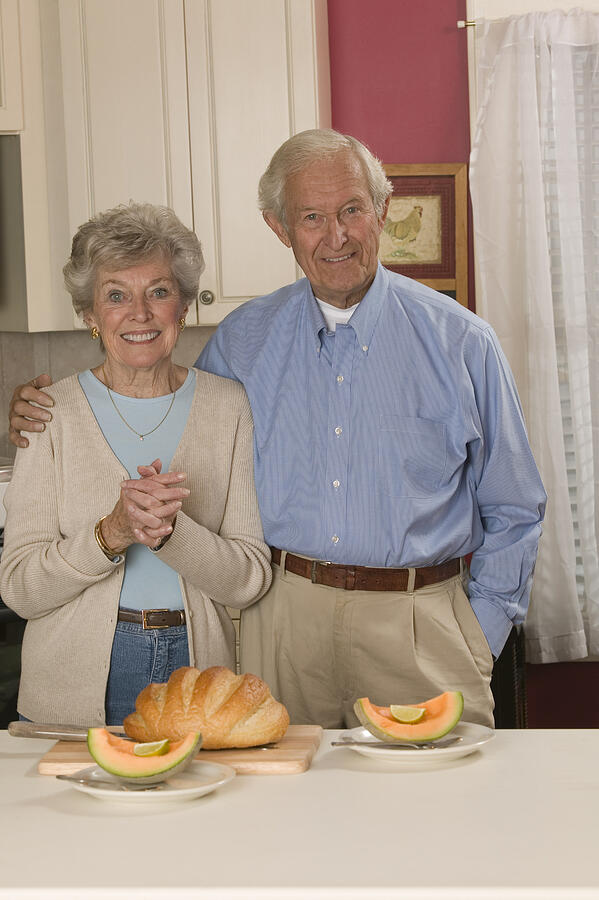 Couple with sliced cantaloupe Photograph by Comstock Images