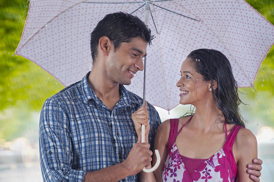 Couple with umbrella enjoying the rain Photograph by IndiaPix/IndiaPicture