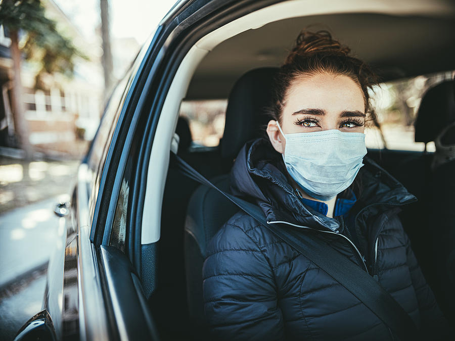 COVID-19, Young woman wearing disposable face mask while driving Photograph by Fotografia Inc.