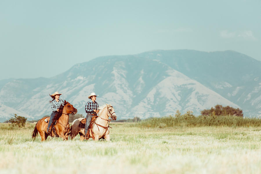 Cowboy couple horseback riding Photograph by Ferrantraite