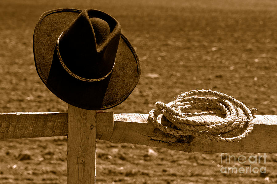 Cowboy Hat and Rope on a Fence - Sepia Photograph by Olivier Le Queinec