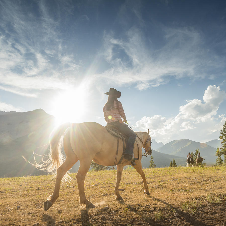 Cowgirl follows companions across mountain meadow Photograph by Ascent Xmedia