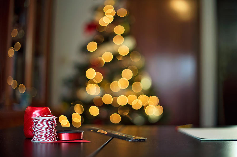 Cozy Christmas. Table with ribbons crafts with Christmas tree behind Photograph by Sol de Zuasnabar Brebbia