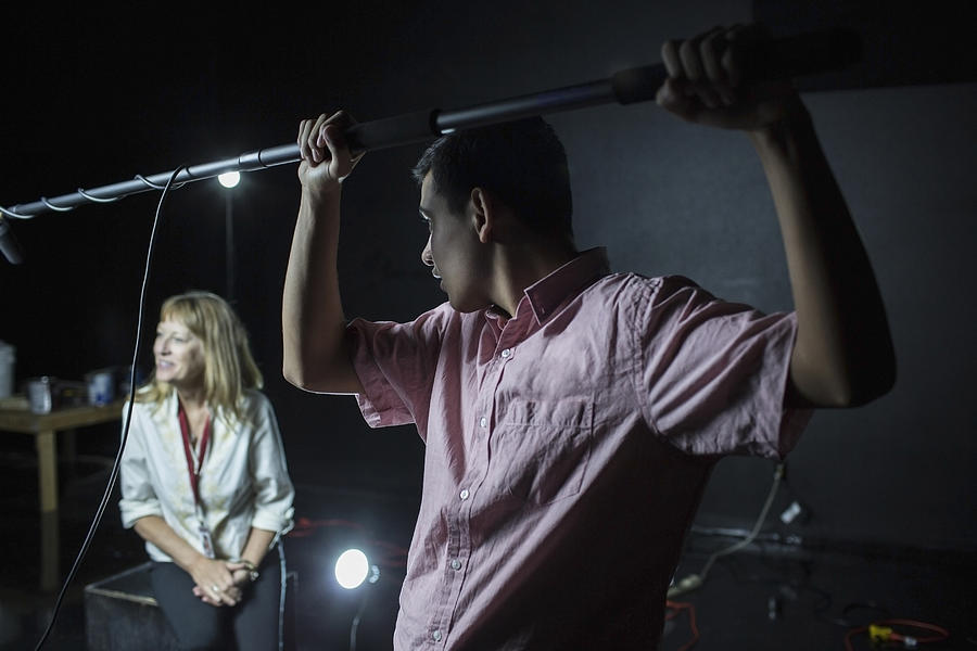 Crew member holding boom microphone on set Photograph by Hill Street Studios