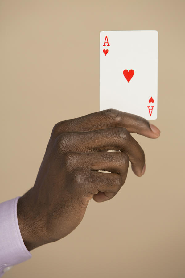 Cropped hand holding ace card against colored background Photograph by Hudzilla