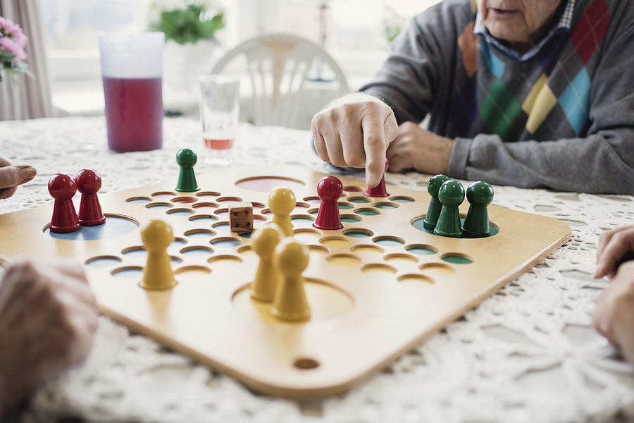 Cropped image of people playing Ludo in nursing home Photograph by Maskot