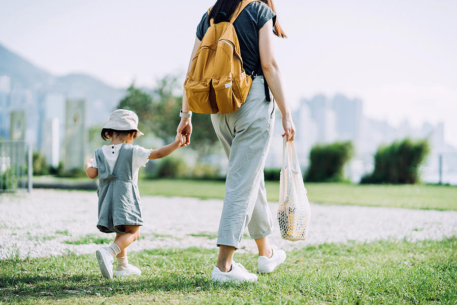 Cropped shot of young Asian mother carrying groceries with cotton mesh eco bag. Walking hand in hand with little daughter across parkland after grocery shopping together. Zero waste concept Photograph by D3sign