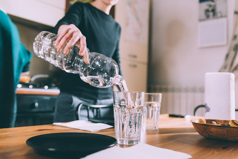 Cropped shot of young woman pouring water at kitchen table Photograph by Eugenio Marongiu