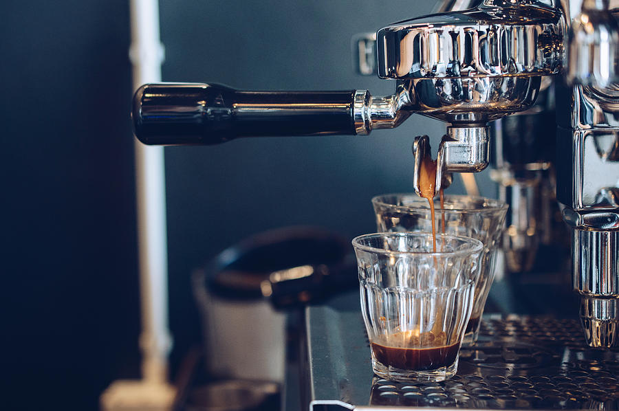 Cropped shot view of espresso pouring from coffee machine. Professional coffee brewing. Photograph by Boy_Anupong